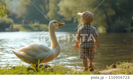 A five-year-old boy in plaid shorts and a plaid cap, together with a large white goose 110956728