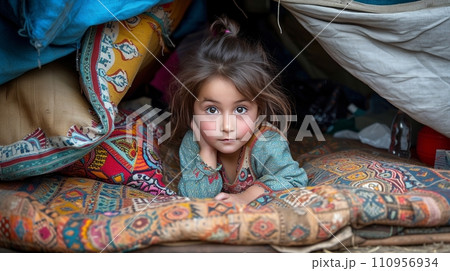 A little girl plays with dolls in a makeshift hut made of pillows and blankets 110956934