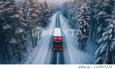 a large red lonely truck drives along the road through the endless winter forest a large red lonely truck drives along the road through the endless winter forest 110957274