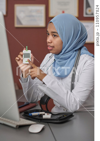 Young female doctor in hijab talking about importance of glucometer to her patient during video call Young female doctor in hijab talking about importance of glucometer to her patient during video call 110957824