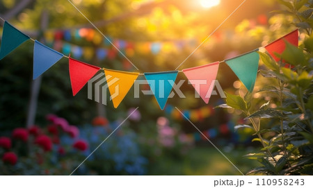 multi-colored garland in the form of triangular flags on a blurred background of a summer garden multi-colored garland in the form of triangular flags on a blurred background of a summer garden 110958243