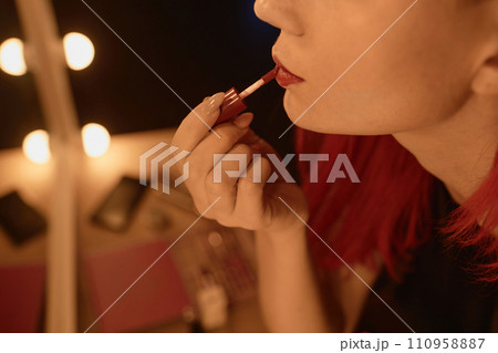 Close up shot of unrecognizable female performer putting on red lipstick in dressing mirror light backstage Close up shot of unrecognizable female performer putting on red lipstick in dressing mirror light backstage 110958887