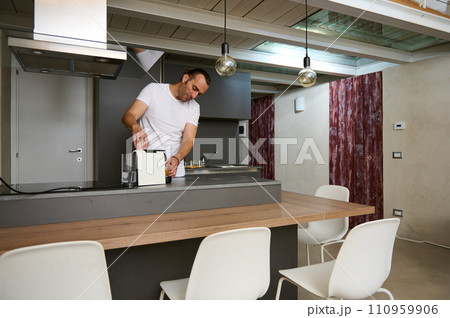 Lifestyle portrait of a handsome young adult man preparing espresso with espresso machine 110959906