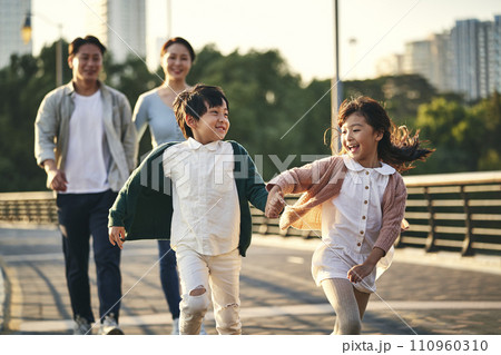 happy asian family with two children walking on pedestrian bridge in city park happy asian family with two children walking on pedestrian bridge in city park 110960310
