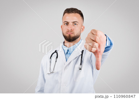 Male doctor showing disapproval with a thumbs-down gesture 110960847