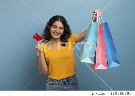 Happy young eastern lady with shopping bags and credit card Happy young eastern lady with shopping bags and credit card 110960890