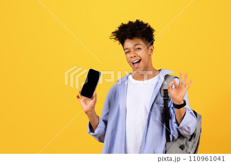 Happy black male student showing phone with blank screen and okay sign 110961041
