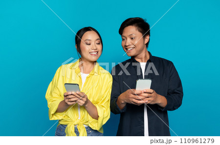 Positive curious korean young man and woman in casual chatting at phone at social networks 110961279