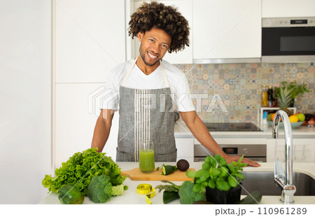 Black man posing with green detox smoothie in glass indoor 110961289