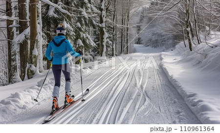 Adventurous cross country skier enjoying a serene winter journey through a beautiful forest trail 110961364