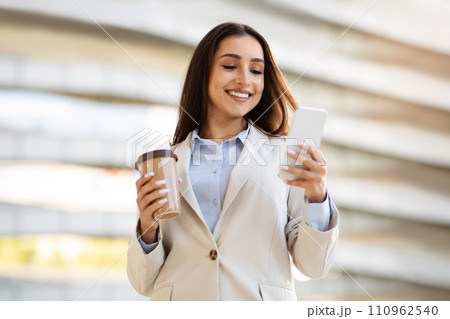 Smiling pretty confident young european woman in suit enjoy work, cup of coffee takeaway Smiling pretty confident young european woman in suit enjoy work, cup of coffee takeaway 110962540