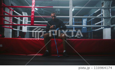 African American boxer sits and wraps his hands with bandage 110964174