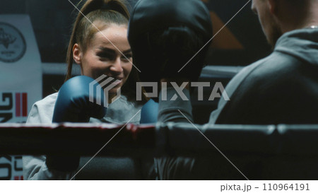 Close up of female boxer in boxing gloves exercising with coach Close up of female boxer in boxing gloves exercising with coach 110964191