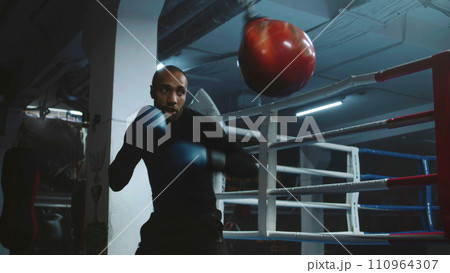 Confident African American fighter hits punching bag while training 110964307
