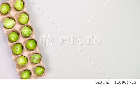 Raw organic Brussel sprouts in brown egg container on grey background, top view. Flat lay, overhead, from above. Copy space. Raw organic Brussel sprouts in brown egg container on grey background, top view. Flat lay, overhead, from above. Copy space. 110965713