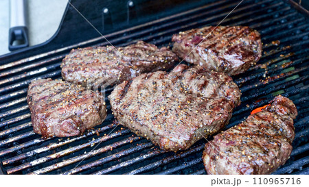 Grilled meat steak on stainless BBQ grill with flames on dark background. Food and cuisine concept. 110965716