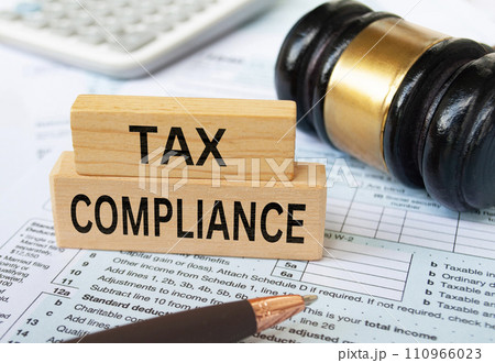 Tax compliance text on wooden blocks with tax form, gavel and calculator background. Taxation concept. 110966023