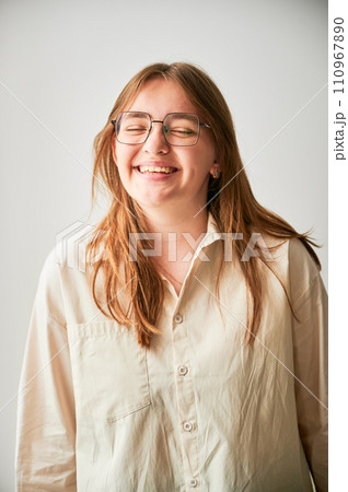 Portrait of beautiful girl smiling to camera. Cute girl in cream shirt and square glasses posing on white background. Portrait of beautiful girl smiling to camera. Cute girl in cream shirt and square glasses posing on white background. 110967890