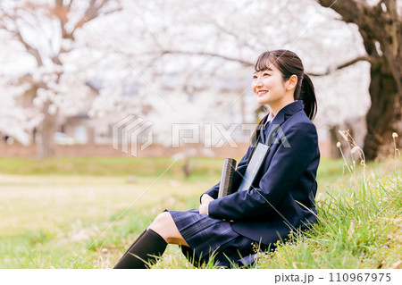 満開の桜の下に座る卒業証書を持つ高校生・女子高生（卒業生・卒業式・卒業） 110967975