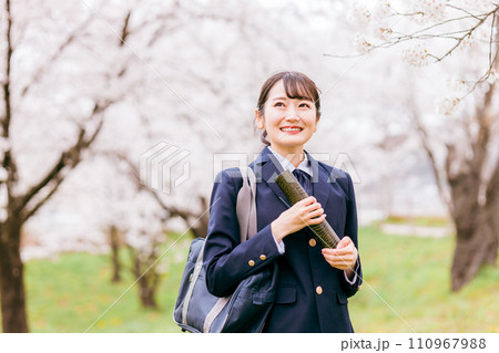 満開の桜並木を歩く卒業証書を持つ高校生・女子高生（卒業生・卒業式・卒業） 110967988