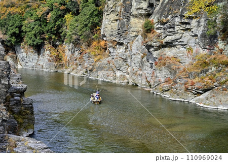 紅葉の長瀞渓谷の岩畳南端付近を流れる荒川に長瀞ライン下りの遊覧船 110969024