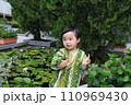 a child clapping hands at a water lily garden, dressed up in Japanese costume  110969430