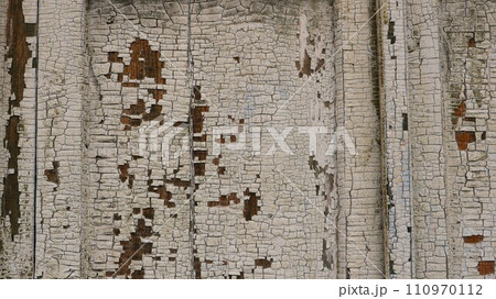 wooden old surface with flaky white paint as a beautiful rough texture with empty copy space, fragment of an aged wood exterior with a peeling coating of white oil paint 110970112