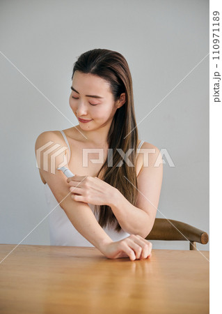 電気シェーバーで腕毛を剃る30代女性 110971189