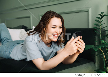 Digital Interaction. Cheerful Woman Socializes, Typing on Smartphone. Relaxed Social Media Time Digital Interaction. Cheerful Woman Socializes, Typing on Smartphone. Relaxed Social Media Time 110972136