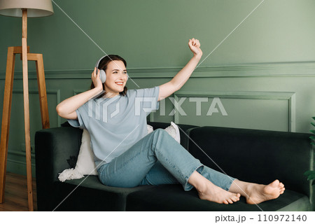 Happy young woman in wireless headphones listening to music while dancing. Rhythmic Euphoria. Joyful Happy young woman in wireless headphones listening to music while dancing. Rhythmic Euphoria. Joyful 110972140