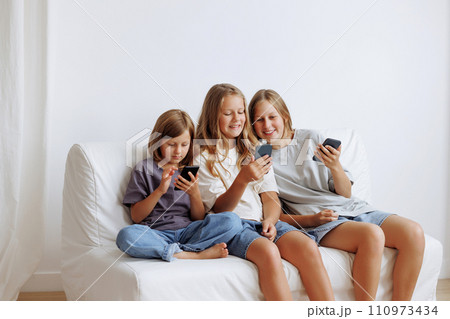 Three girl using smartphones on couch 110973434