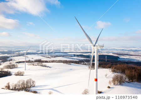 Aerial view of winter meadow with wind turbines generating electricity Aerial view of winter meadow with wind turbines generating electricity 110973540