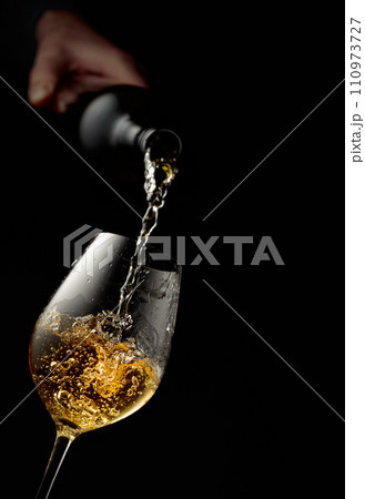 Pouring white wine into a glass. 110973727