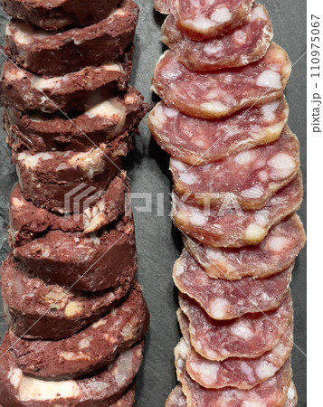 Slices of sausage and meat pudding on a plate, top view 110975067
