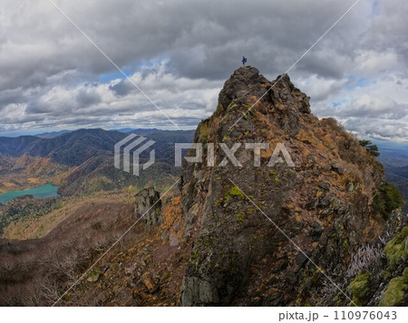ジャンダルムからの恵庭岳本峰に立つ登山者 110976043