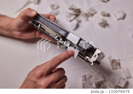 Changing the thermal paste on the graphics processor. Disassembled graphics card on the table. Old graphics card service. Changing the thermal paste on the graphics processor. Disassembled graphics card on the table. Old graphics card service. 110976678