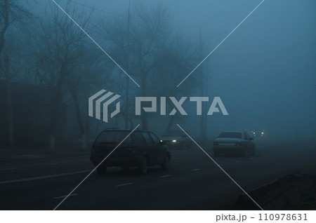 road with cars in city on a foggy morning in autumn in fog mist road with cars in city on a foggy morning in autumn in fog mist 110978631