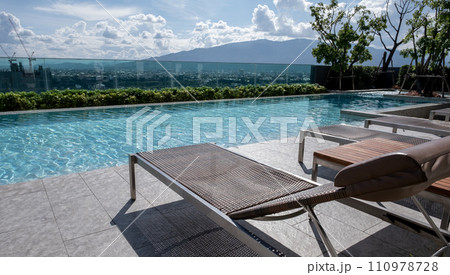 Picture of a sun bed chair on the edge of a hotel or resort rooftop swimming pool 110978728