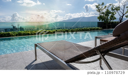 Picture of a sun bed chair on the edge of a hotel or resort rooftop swimming pool 110978729
