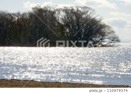 午後の日差しできらきら光る湖面 110979374