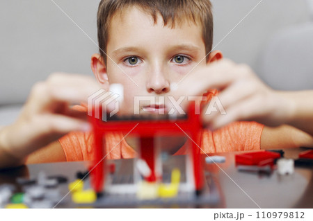 Boy Intently Assembling a Red Toy Building Set Boy Intently Assembling a Red Toy Building Set 110979812