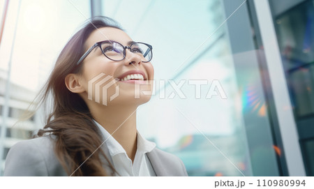 Generative AI The image features a young woman with glasses looking up and smiling, illuminated by natural light indoors. 110980994