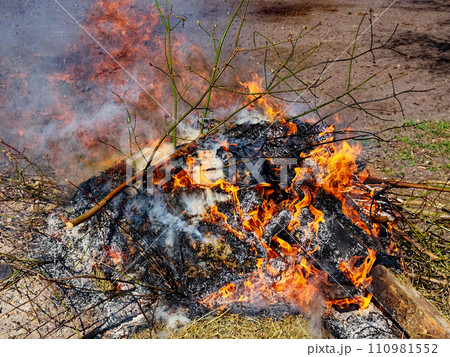 Orange flames and smoke emanate from burnt wood. Orange flames and smoke emanate from burnt wood. 110981552