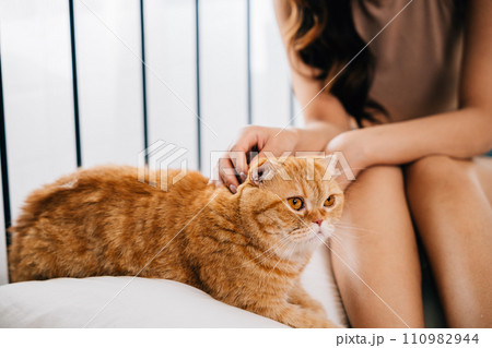 A woman and her furry friend, a Scottish Fold cat, find happiness in each other's company while lying in bed. Their togetherness and playful bonding radiate joy and relaxation. A woman and her furry friend, a Scottish Fold cat, find happiness in each other's company while lying in bed. Their togetherness and playful bonding radiate joy and relaxation. 110982944