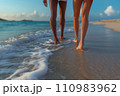 legs of a couple walking along the beach in the surf 110983962