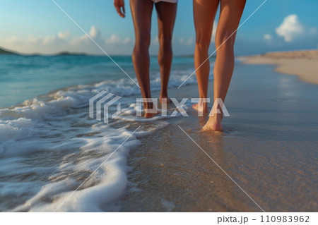 legs of a couple walking along the beach in the surf 110983962