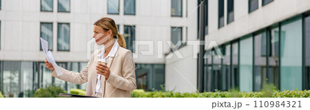 Stylish woman analyst working with documents while sitting outside on modern building background 110984321