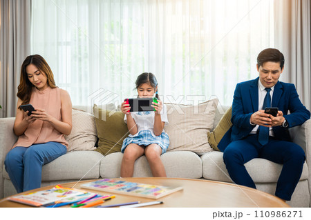 Family don't care about each other. Asian parents ignore their child and looking at their mobile phone at home, gadgets dependence overuse internet social media addiction on sofa living room Family don't care about each other. Asian parents ignore their child and looking at their mobile phone at home, gadgets dependence overuse internet social media addiction on sofa living room 110986271