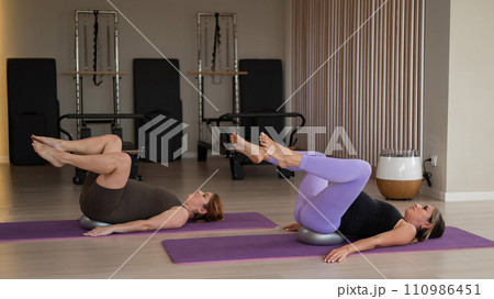 Two pregnant women doing Pilates with special small fit balls. Two pregnant women doing Pilates with special small fit balls. 110986451