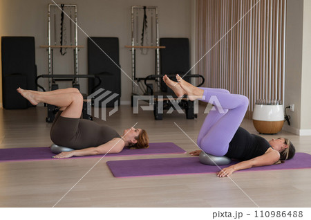 Two pregnant women doing Pilates with special small fit balls. Two pregnant women doing Pilates with special small fit balls. 110986488